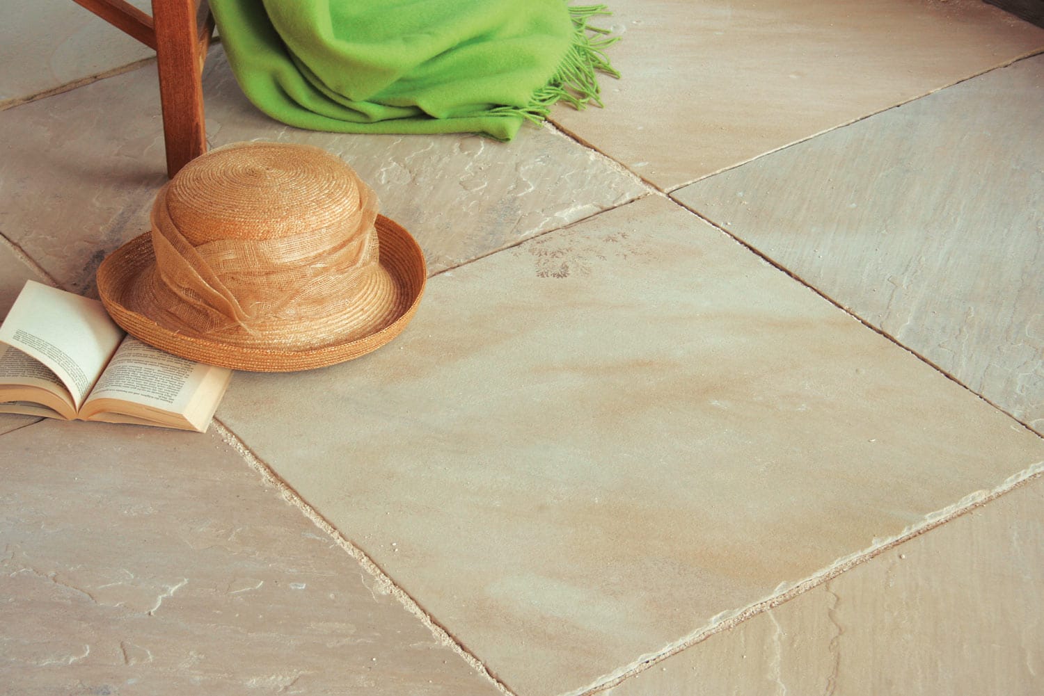Terrasse mit Bodenplatten Sandstein Mint oder Hartsandstein Sahara mit Buch und Hut im Vordergrund